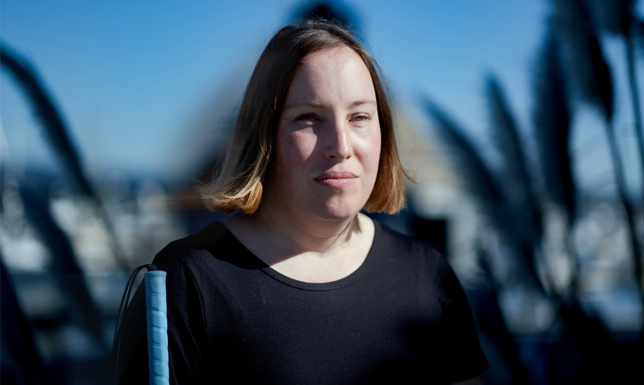 visually impaired woman walking outside holding a blue cane