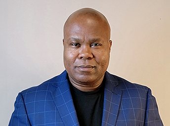 Black bald men wearing a blue plaid jacket on grey background