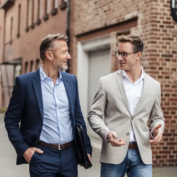 Two businessmen talking next to a brick building
